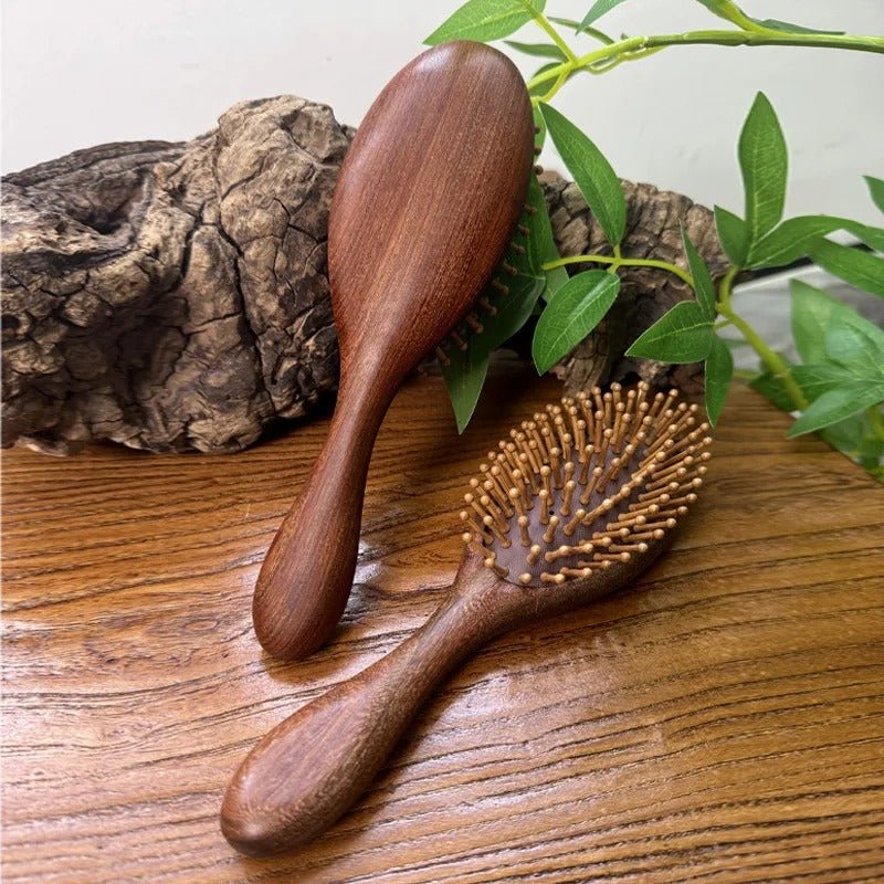 Brosse à cheveux en bois de santal de forme ronde appuyée sur une pièce de bois et une autre posée sur un plan en bois