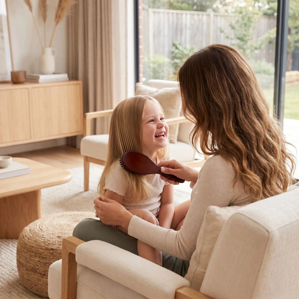 brosse poil de sanglier naturel jeune femme qui coiffe sa fillette souriante