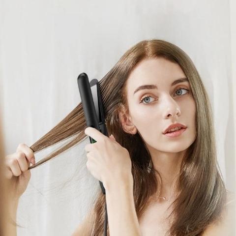 jeune femme aux cheveux longs bruns qui se coiffe avec le lisseur mini noir