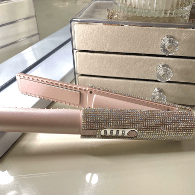 Lisseur sans fil rose posé sur une table de maquillage