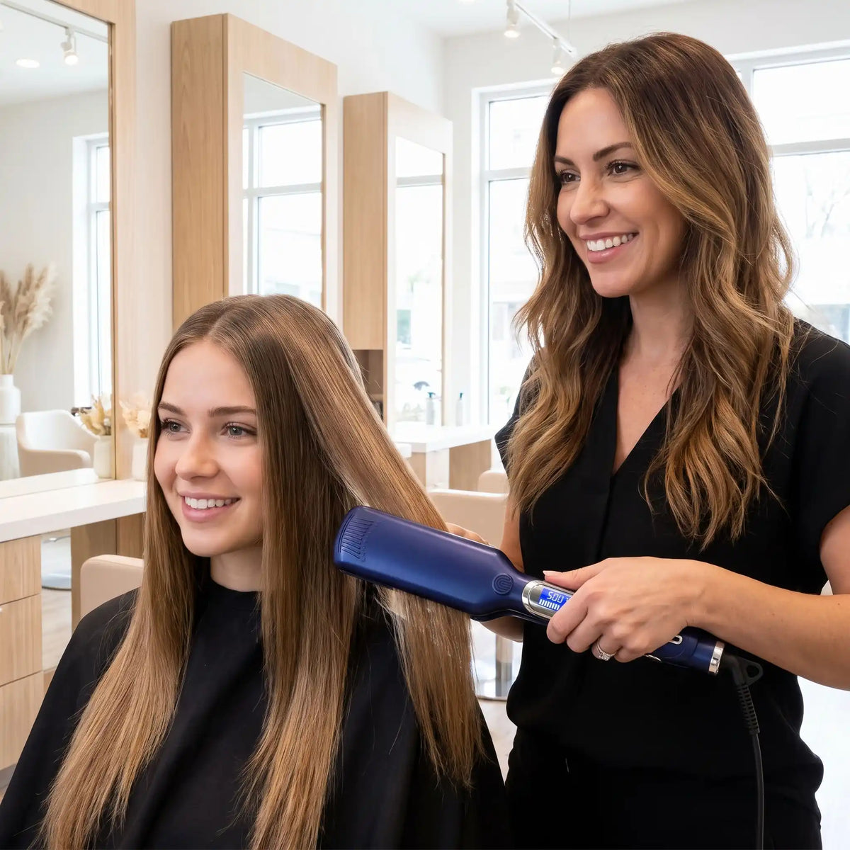 professionnelle de la coiffure qui lisse les cheveux de sa cliente avec le lisseur bleu nuit