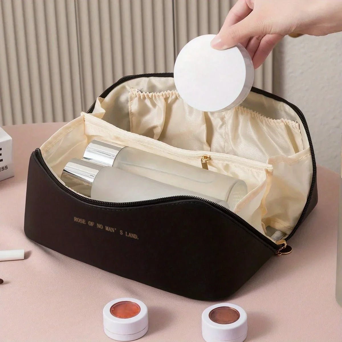 Une femme qui place des produits de maquillage dans la trousse de toilette couleur noire
