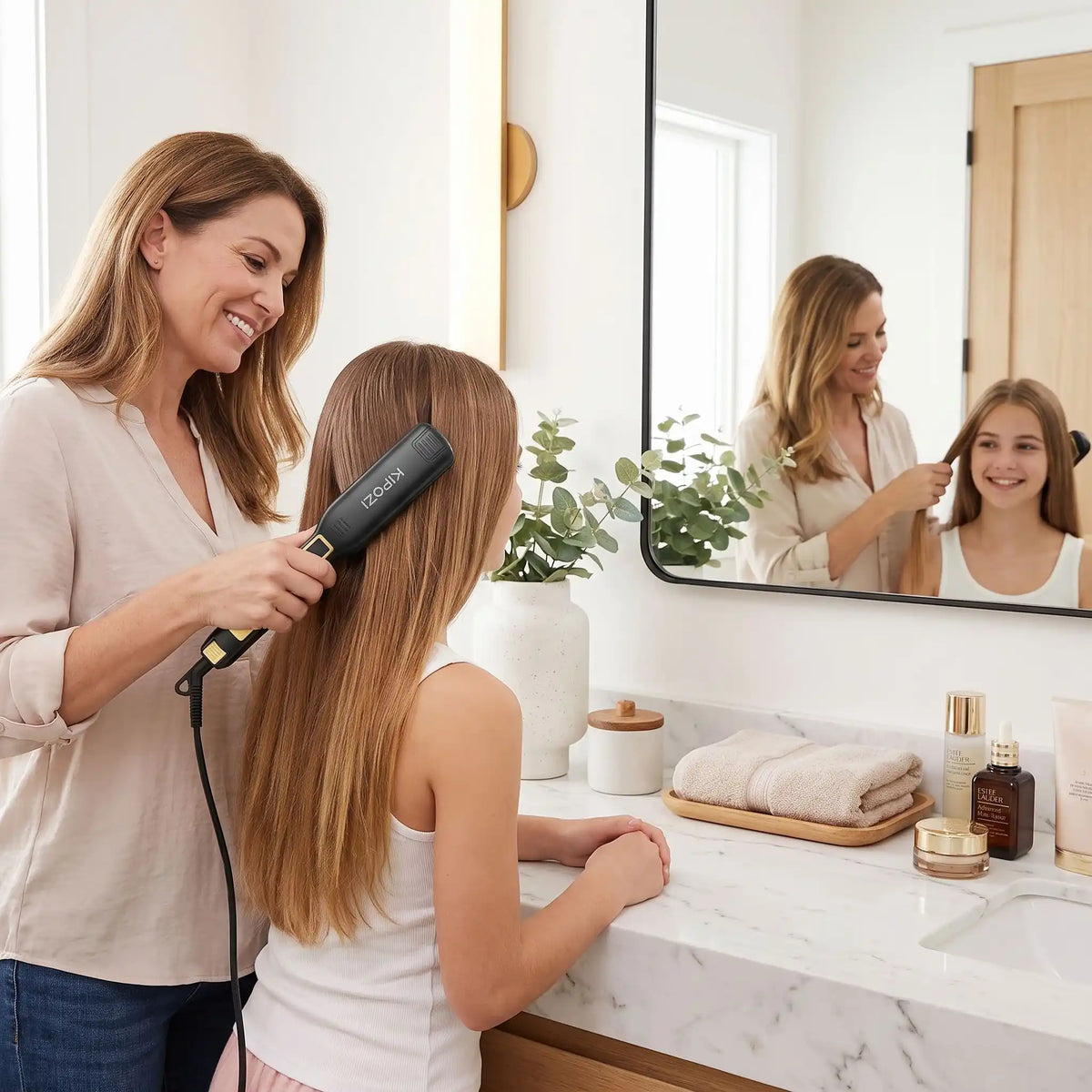 une maman qui coiffe sa jeune adolescente avec le lisseur cheveux devant le miroir