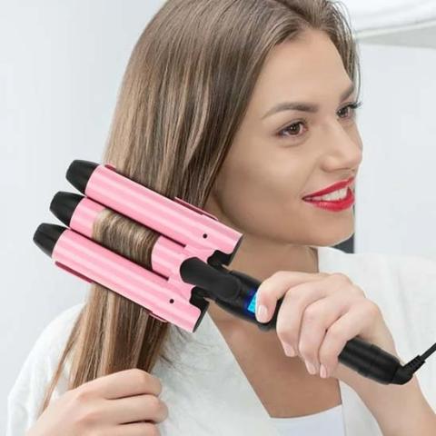 Jeune femme souriante utilisant le boucleur 3 tubes rose