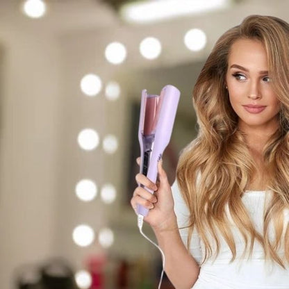 Jeune femme aux longs cheveux châtains blonds regardant son boucleur qu'elle tient dans sa main