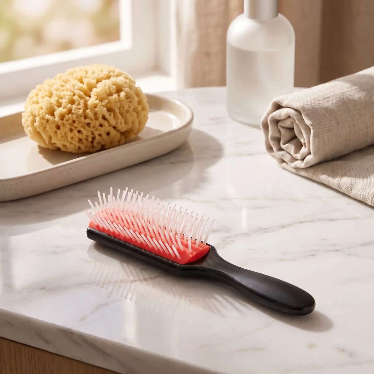 brosse à cheveux rouge posée sur un plan blanc et gris