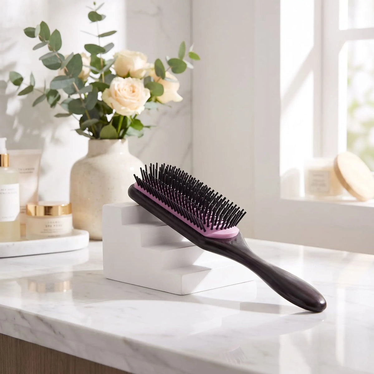 brosse à cheveux violet posée sur un plan blanc