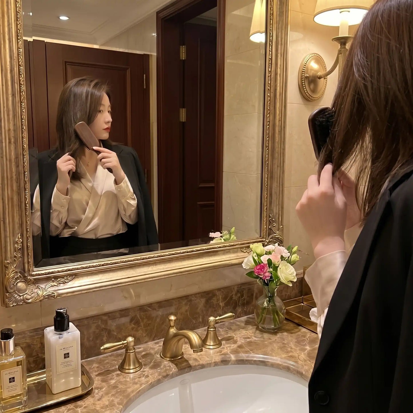 Jeune femme qui se coiffe dans le miroir avec la brosse poil de sanglier