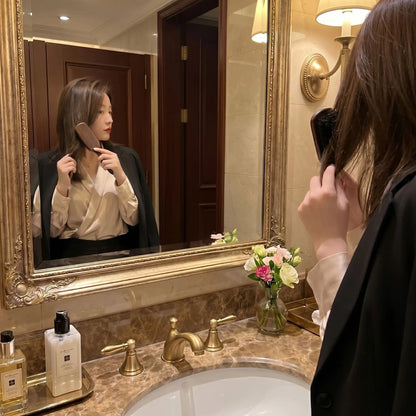 Jeune femme qui se coiffe dans le miroir avec la brosse poil de sanglier