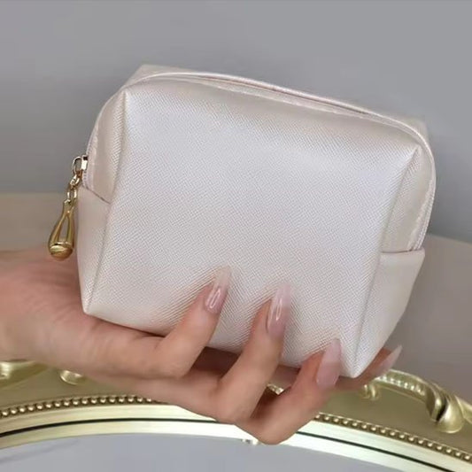 une femme qui tient la trousse de toilette couleur crème 