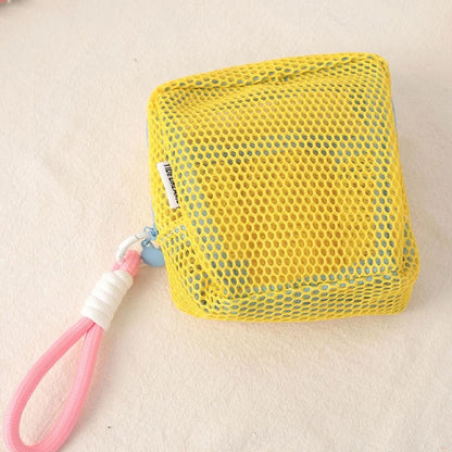 Trousse de toilette couleur jaune posée sur un plan décoratif crème