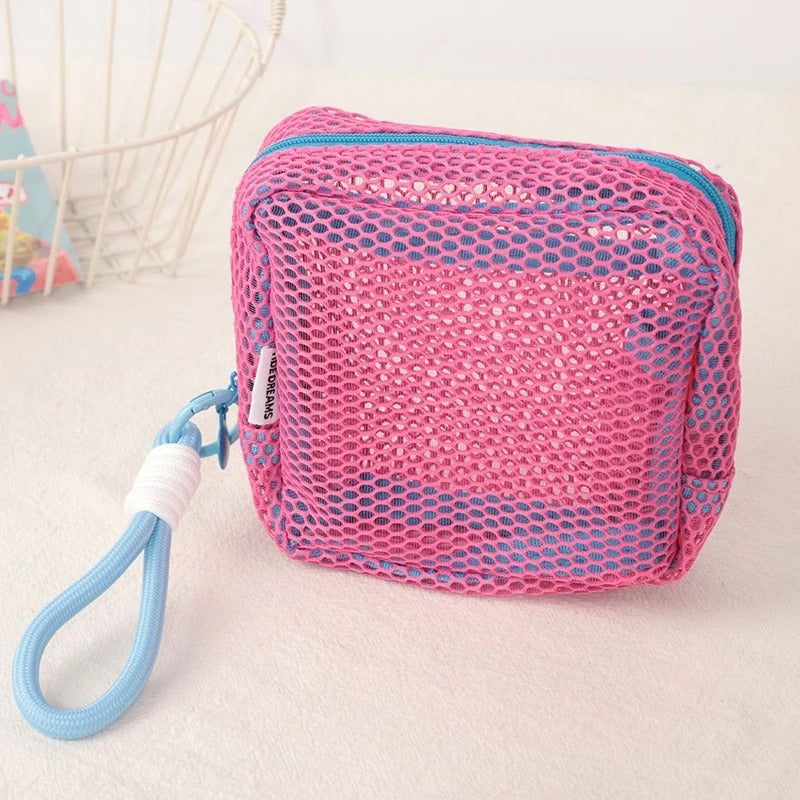 Trousse de toilette couleur rose posée sur un plan décoratif crème
