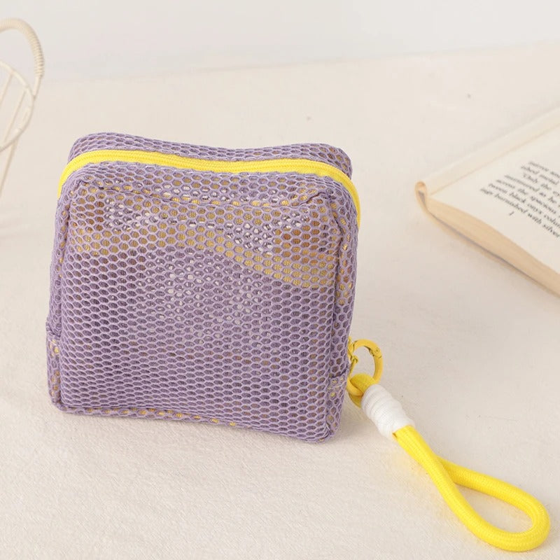 Trousse de toilette couleur violet posée sur un plan décoratif crème