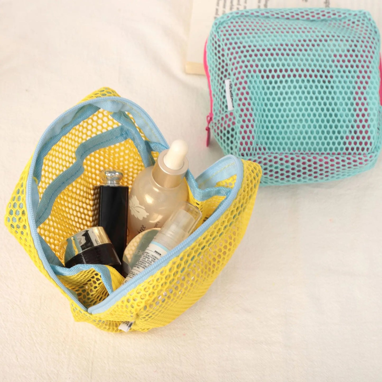 Trousse de toilette de couleur jaune et cyan posées sur un plan blanc 