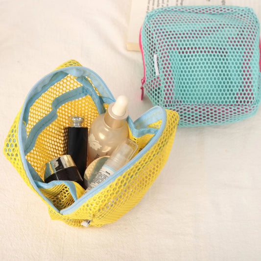 Trousse de toilette de couleur jaune et cyan posées sur un plan blanc 