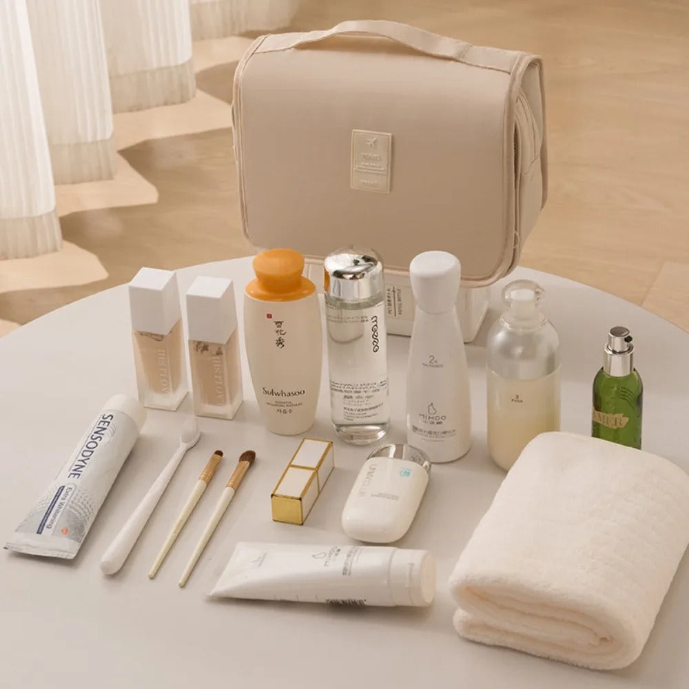 trousse de toilette nylon couleur beige posée sur une table blanche avec articles de toilette posés devant elle