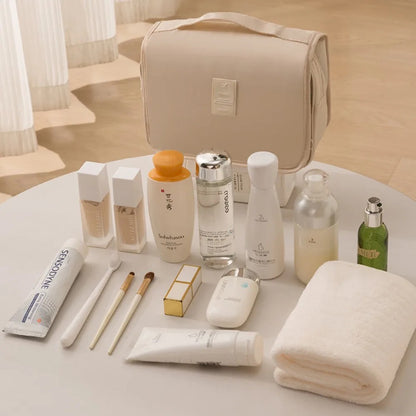 trousse de toilette nylon couleur beige posée sur une table blanche avec articles de toilette posés devant elle
