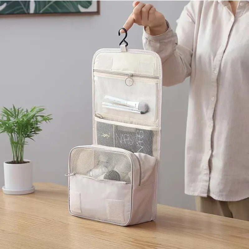 une femme qui tient la trousse de toilette suspendue afin d'en apprécier toutes les caractéristiques