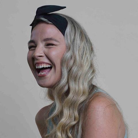 Une jeune femme d'environ 20-25 ans souriante qui porte le bandeau cheveux couleur noire