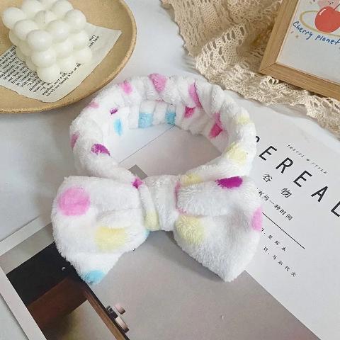 Bandeau cheveux couleur blanc à pois posé sur un table blanche