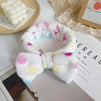 Bandeau cheveux couleur blanc à pois posé sur un table blanche