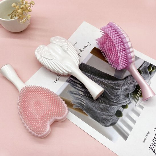 Brosse à cheveux 3 coloris posée sur un plan rose 