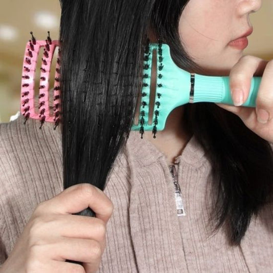 jeune femme d'environ 25 ans qui se coiffe les cheveux avec la brosse à cheveux à poils mixtes