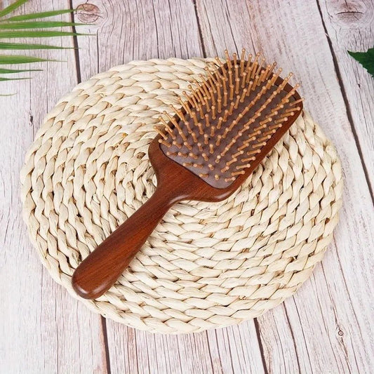 Brosse à cheveux en bois de santal format carré posé sur un paillis tressé rond