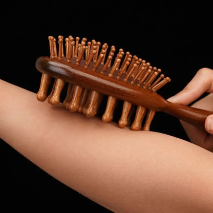 Une main qui tient la brosse à cheveux double face et qui passe les poils de la brosse sur son avant-bras pour démontrer leur douceur 