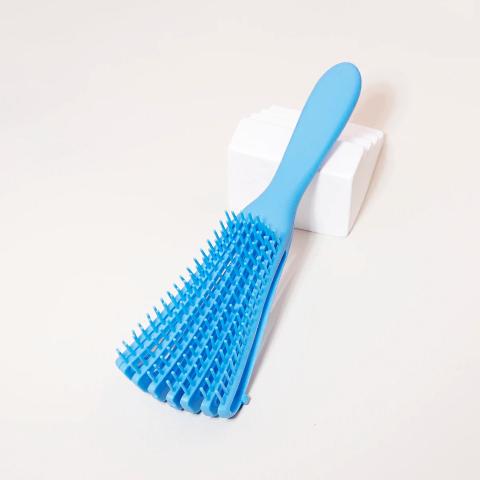 Brosse à cheveux bouclés pour cheveux épais de couleur bleue posé sur un plan blanc 