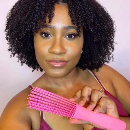 Jeune femme type afro qui tient la brosse à cheveux bouclés pour cheveux épais de couleur rose 