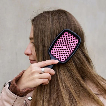 Jeune femme de profil longs cheveux châtains qui brosse ses cheveux avec la brosse à cheveux démêlante de couleur rose
