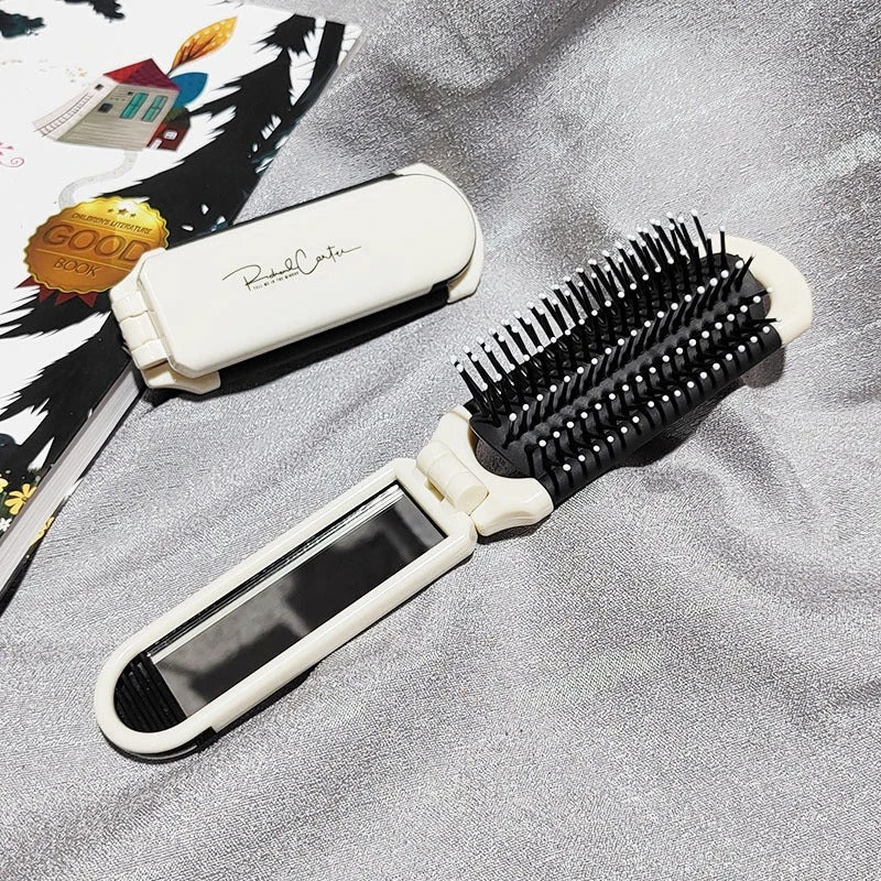 Brosse à cheveux démêlante de couleur blanche montrée pliée et dépliée posée sur une pièce de tissus argenté 