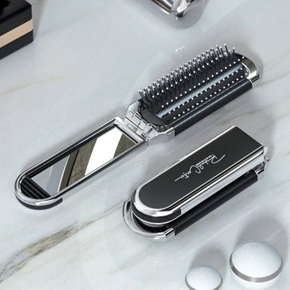 Brosse à cheveux démêlante de couleur argentée montrée pliée et dépliée posée sur un comptoir blanc