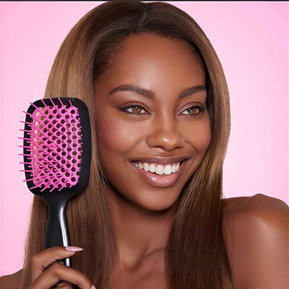 Jeune femme souriante aux longs cheveux châtains qui tient la brosse à cheveux démêlante 