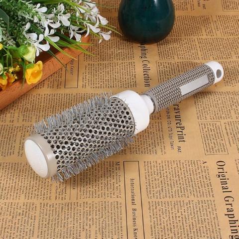 Brosse à cheveux posée sur un journal style vieillot avec fleurs jaunes et blanches en élément décoratif 