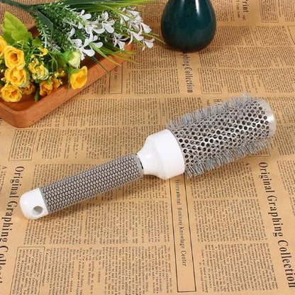 Brosse à cheveux posée sur un journal style vieillot avec fleurs jaunes et blanches en élément décoratif et pot de fleur vert foncé 