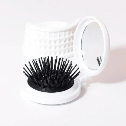 Brosse a cheveux couleur blanche poils noirs posée sur un plan blanc
