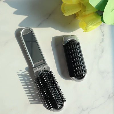 Brosse à cheveux démêlante montrée pliée et dépliée posée sur un comptoir tulipes jaunes en décoration