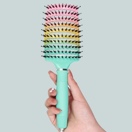Brosse à cheveux à poils mixtes tenue par une main de femme afin d'en apprécier toutes les caractéristiques