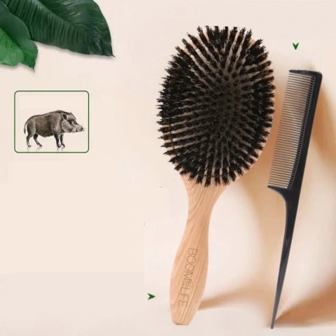 Brosse à Poil de Sanglier grand format adossée sur un mur beige et un peigne à cheveux à ses côtés 