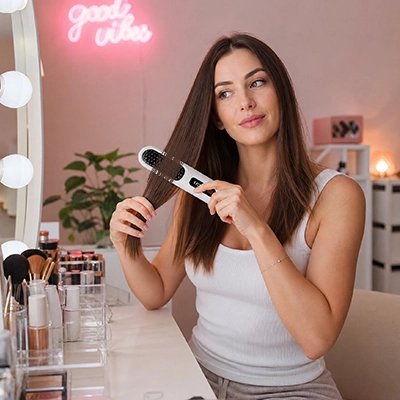 Brosse chauffante blanche jeune femme qui se coiffe avec la brosse 
