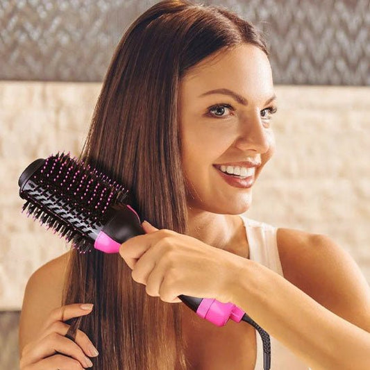 Jeune femme cheveux longs bruns qui se coiffe avec la brosse chauffante à air chaud de couleur noir et rose