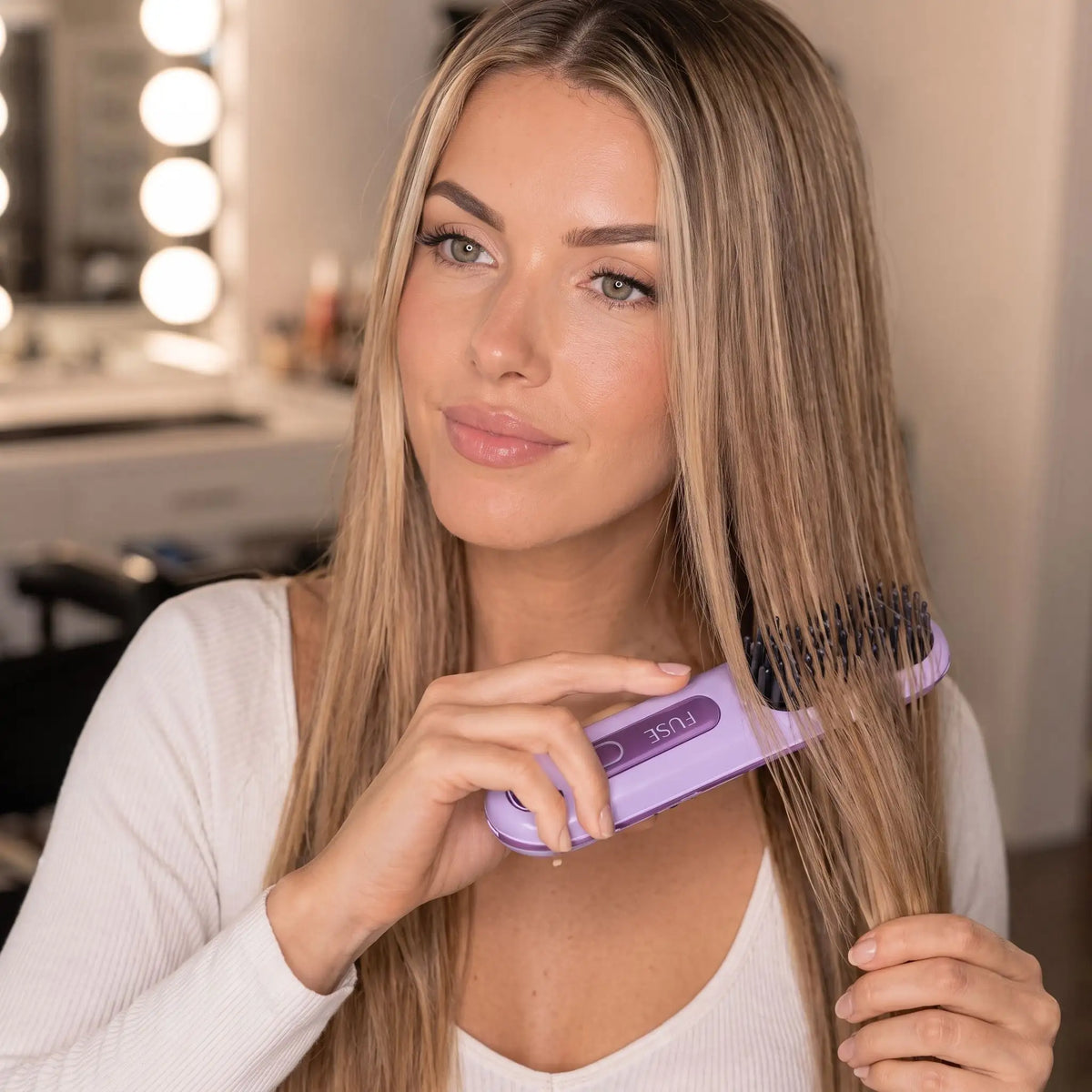 brosse chauffante jeune femme aux cheveux blonds qui se coiffe