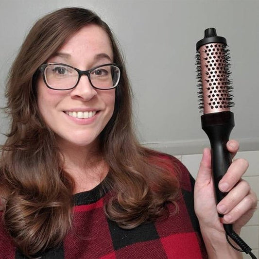 Jeune femme d'environ 25-30 ans qui tient la brosse chauffante volumisante afin qu'on puisse en apprécier toutes les caractéristiques