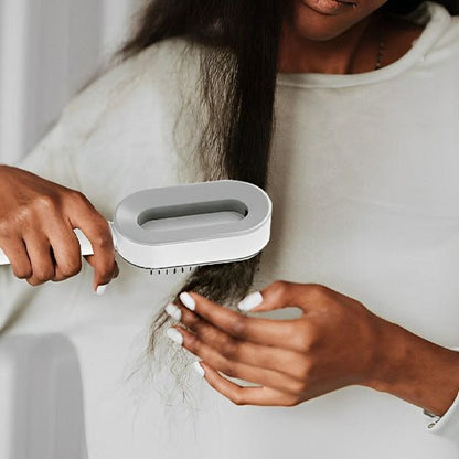 jeune femmes longs cheveux noirs bouclés qui se coiffe avec la brosse cheveux autonettoyante de couleur grise blanche