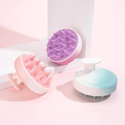 brosse cheveux massage trois couleurs posées sur un plan rose et blanc