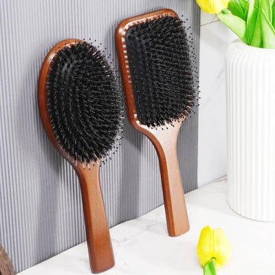 Brosse poil de sanglier format carré et rond adossées contre un mur gris