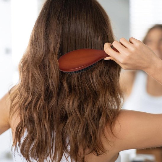Brosse poil de sanglier jeune femme de dos qui coiffe ses longs cheveux châtains