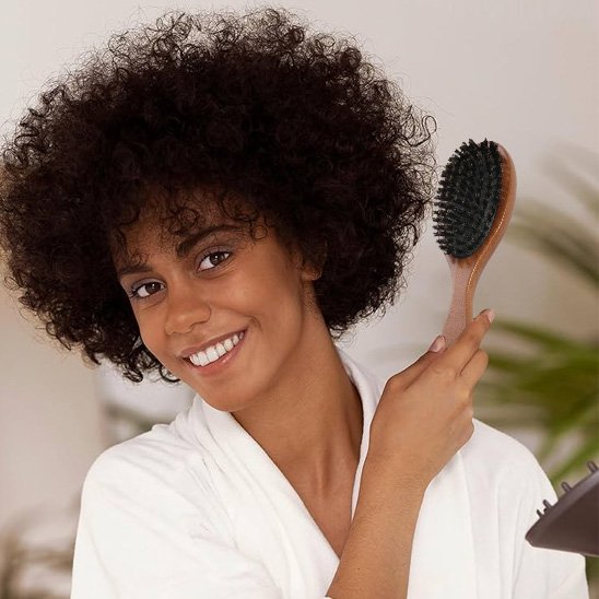 Brosse poil de sanglier jeune femme qui se coiffe avec la brosse 